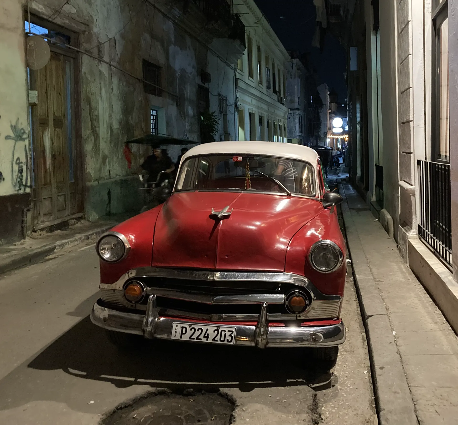 Roter Oldtimer in einer Gasse in Havanna